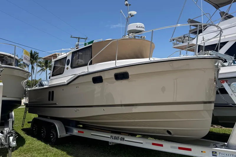 The Image of 2025 Ranger Tugs R-27 boat on trailer, displayed outdoors under clear blue sky. - 0