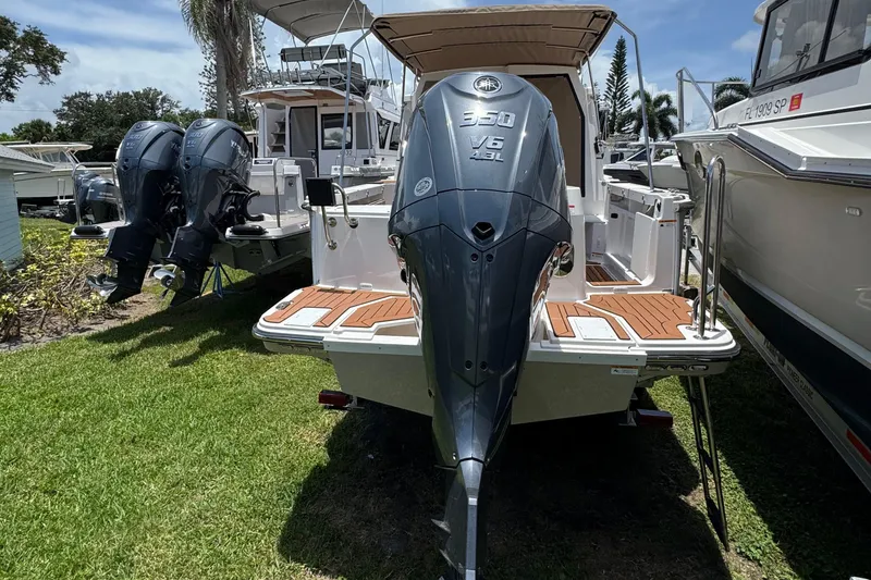 Slide: The Image of 2025 Ranger Tugs R-27 boat with powerful 350 V6 outboard engine, docked on grass. - 10