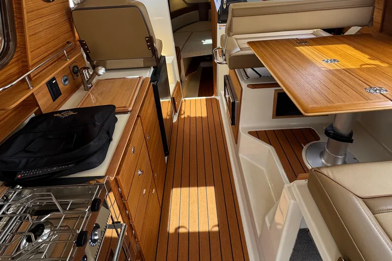 Slide: The Image of 2025 Ranger Tugs R-27 interior with wood finish, kitchenette, and seating area. - 7