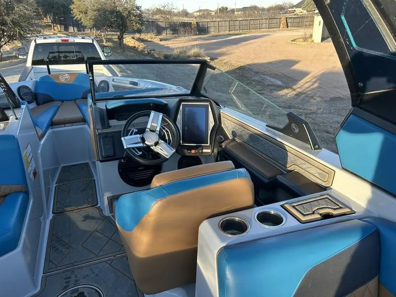 Slide: The Image of 2023 Tigé Z5 boat interior with blue and brown seating, modern dashboard, and steering wheel. - 12