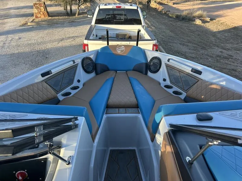 Slide: The Image of 2023 Tigé Z5 boat interior with blue and brown seating, parked behind a white truck. - 2