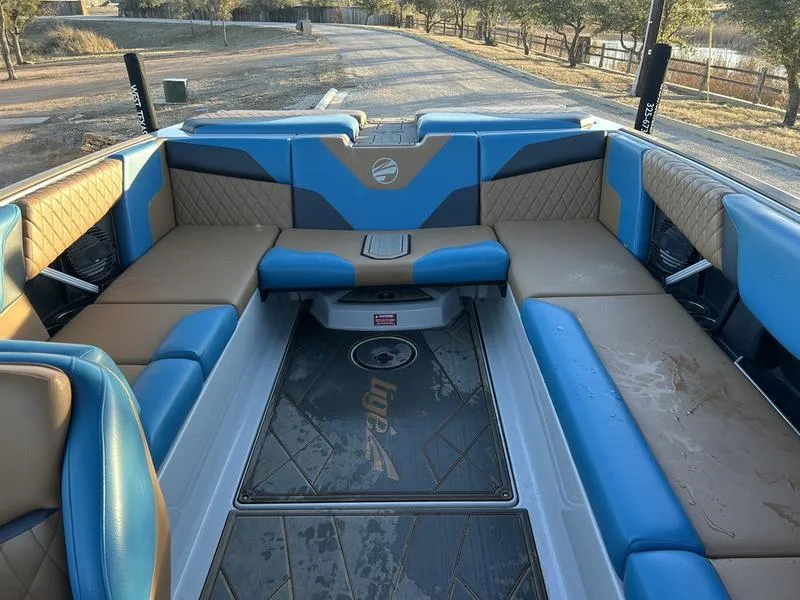Slide: The Image of 2023 Tigé Z5 boat interior with blue and tan seating, parked on a lakeside road. - 5