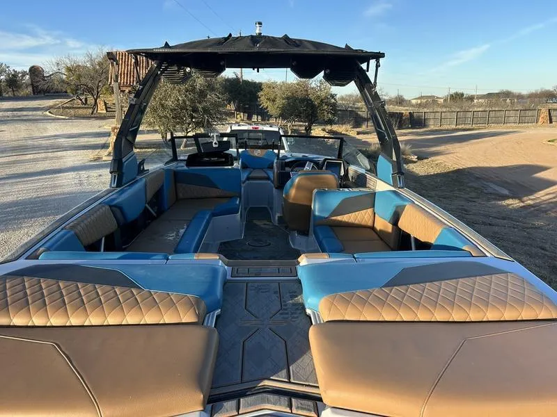 Slide: The Image of 2023 Tigé Z5 boat interior with blue and brown seating, parked outdoors. - 6