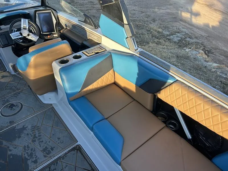 Slide: The Image of 2023 Tigé Z5 boat interior with blue and tan seating, modern dashboard, and cup holders. - 7
