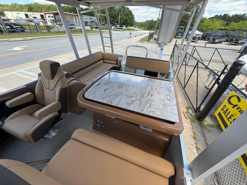 Slide: The Image of 2025 Avalon Catalina Entertainer Funship interior with seating and table, parked near a sales lot. - 22