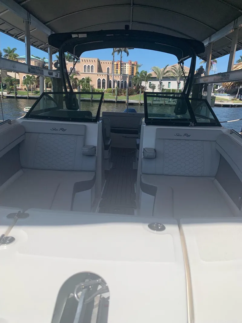 Slide: The Image of 2021 Sea Ray SDX 270 Outboard boat interior with seating, docked near waterfront homes. - 8