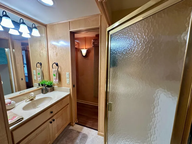 Slide: The Image of Bathroom interior of 2006 Stardust Cruisers 16x78 with wooden cabinetry and glass shower. - 9