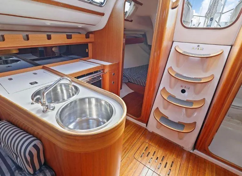 Slide: The Image of Interior of 2000 X-Yachts X-362 Sport, featuring a compact kitchen and wooden cabinetry. - 17