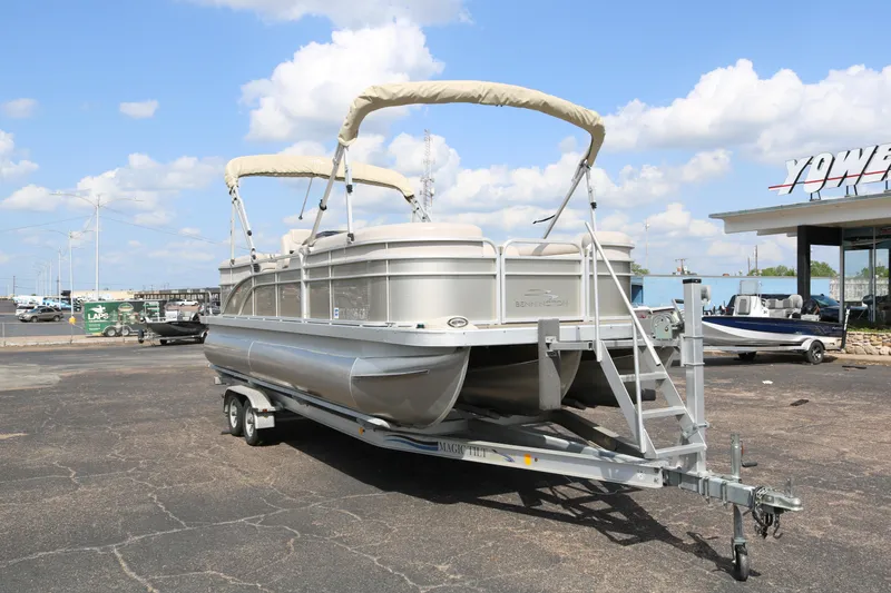 Slide: The Image of 2015 Bennington 24SSRX pontoon boat on trailer, parked outdoors under a blue sky. - 1