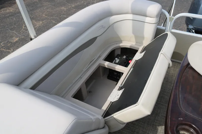 Slide: The Image of 2015 Bennington 24SSRX boat seat storage compartment open, revealing interior space. - 16
