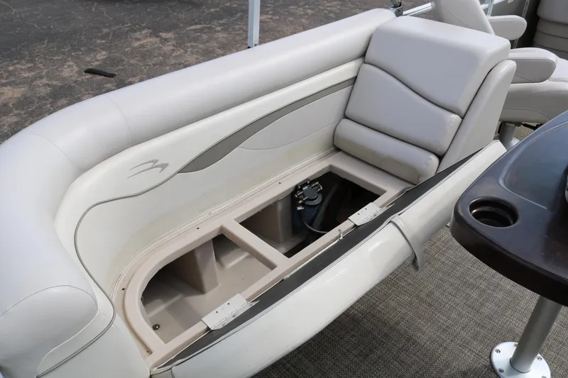 Slide: The Image of 2015 Bennington 24SSRX boat interior with open storage compartment under cushioned seating. - 20