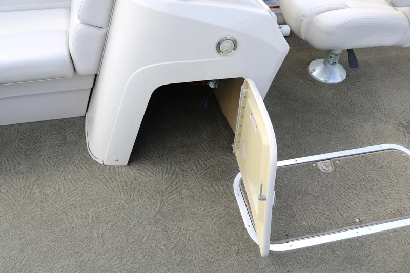 Slide: The Image of 2015 Bennington 24SSRX boat interior storage compartment with open hatch on carpeted floor. - 23
