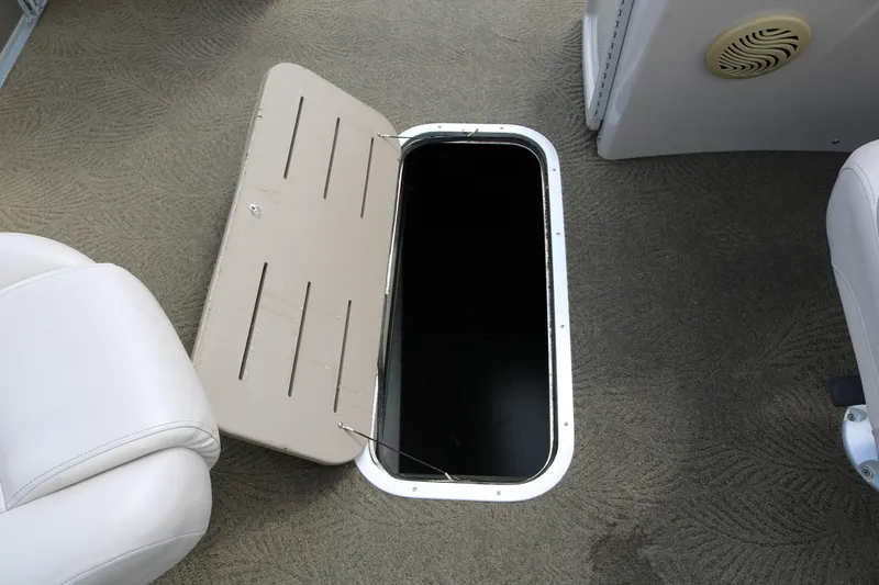 Slide: The Image of Open storage compartment on 2015 Bennington 24SSRX boat, featuring beige interior and seating. - 32