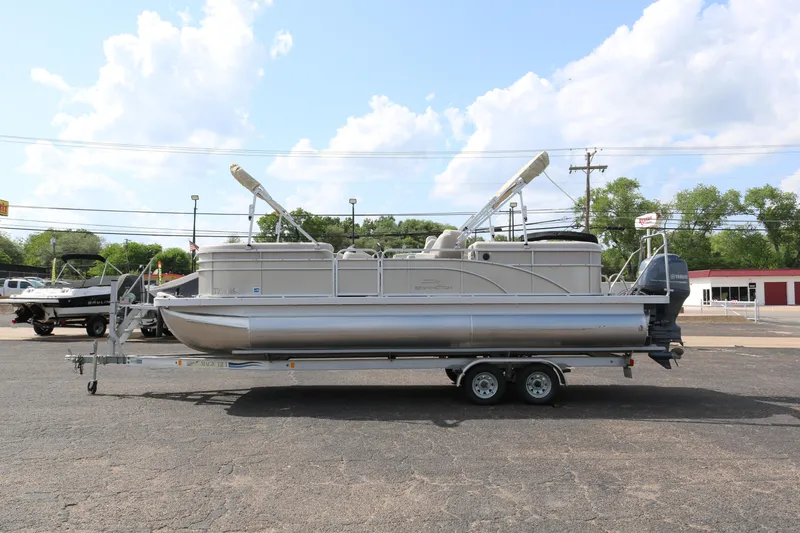 Slide: The Image of 2015 Bennington 24SSRX pontoon boat on trailer, parked outdoors under a blue sky. - 4