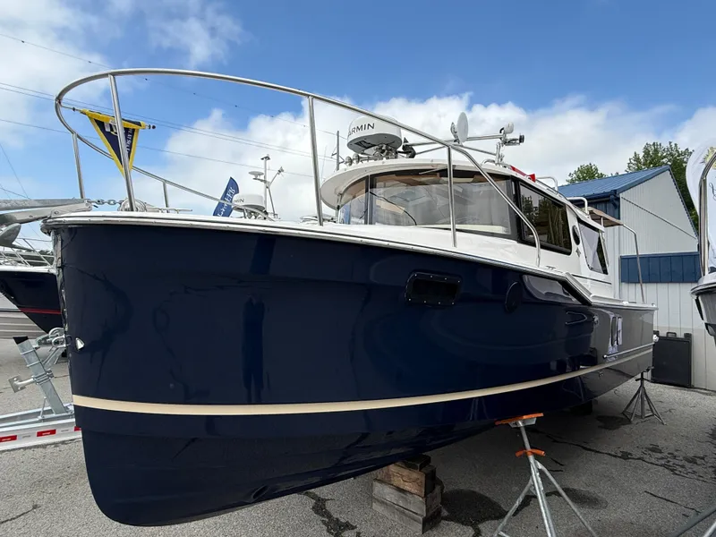 Slide: The Image of 2025 Ranger Tugs R-27 boat with blue hull, docked outdoors under a clear sky. - 0