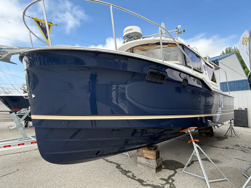 Slide: The Image of 2025 Ranger Tugs R-27 boat with blue hull on display at a marina. - 1