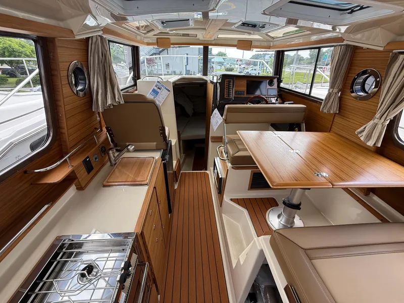 Slide: The Image of Interior of 2025 Ranger Tugs R-27 boat, featuring wood accents and modern amenities. - 12