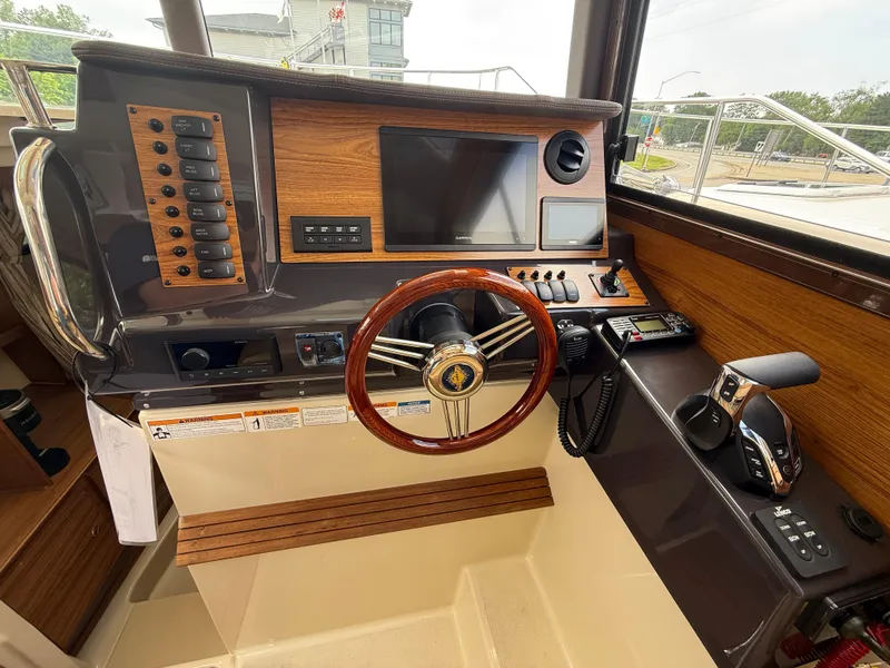 Slide: The Image of 2025 Ranger Tugs R-27 helm with wood accents, steering wheel, and control panel. - 14