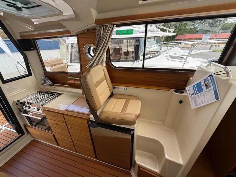 Slide: The Image of 2025 Ranger Tugs R-27 interior with seating, kitchenette, and wood accents. - 15