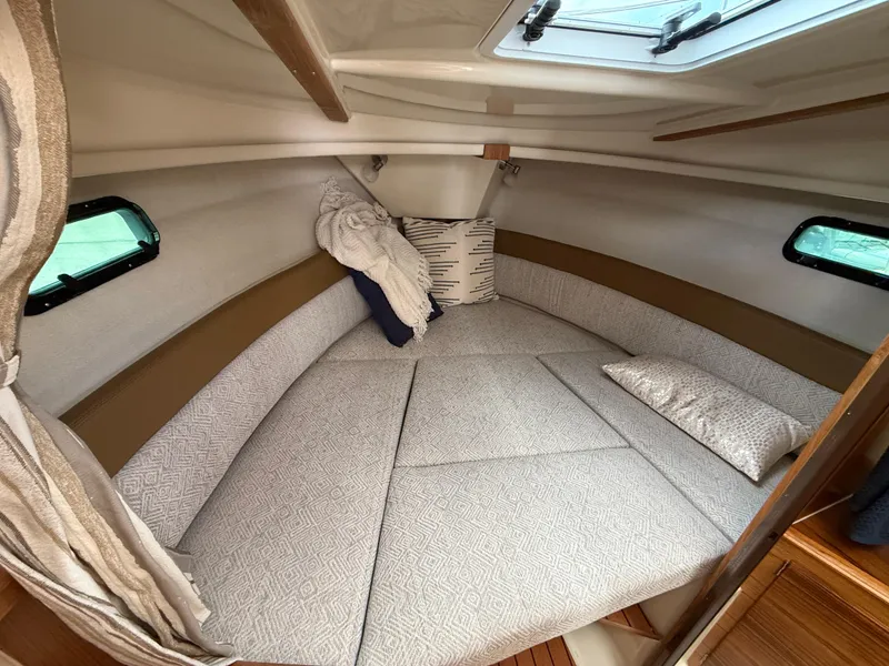 Slide: The Image of 2025 Ranger Tugs R-27 cabin interior with cozy bedding and natural light. - 16