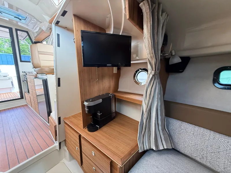 Slide: The Image of 2025 Ranger Tugs R-27 interior with TV, coffee maker, and cozy seating area. - 17