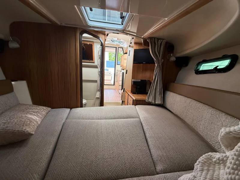 Slide: The Image of Interior of 2025 Ranger Tugs R-27 boat, featuring cozy cabin with bed and natural light. - 18