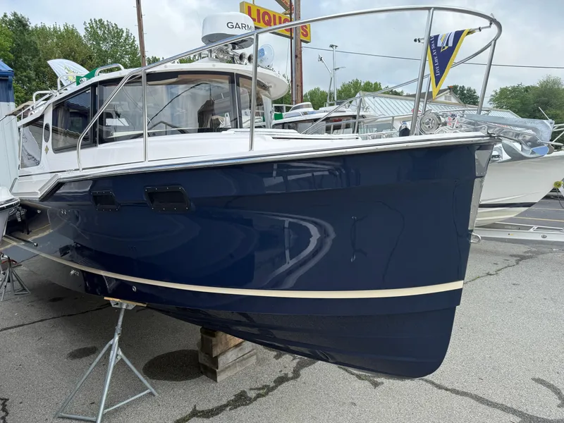 Slide: The Image of 2025 Ranger Tugs R-27 boat with sleek blue hull, displayed outdoors. - 2