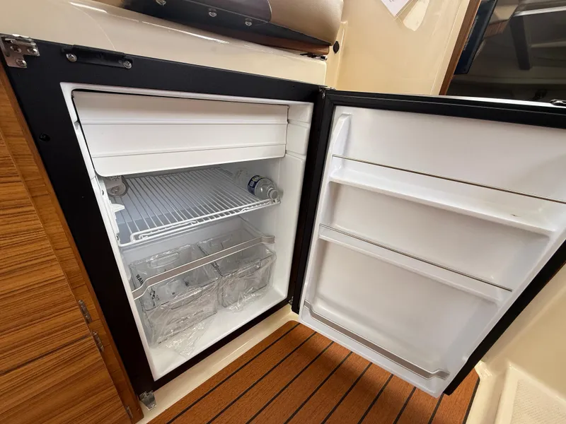 Slide: The Image of Open refrigerator inside 2025 Ranger Tugs R-27 boat, showcasing interior storage space. - 20