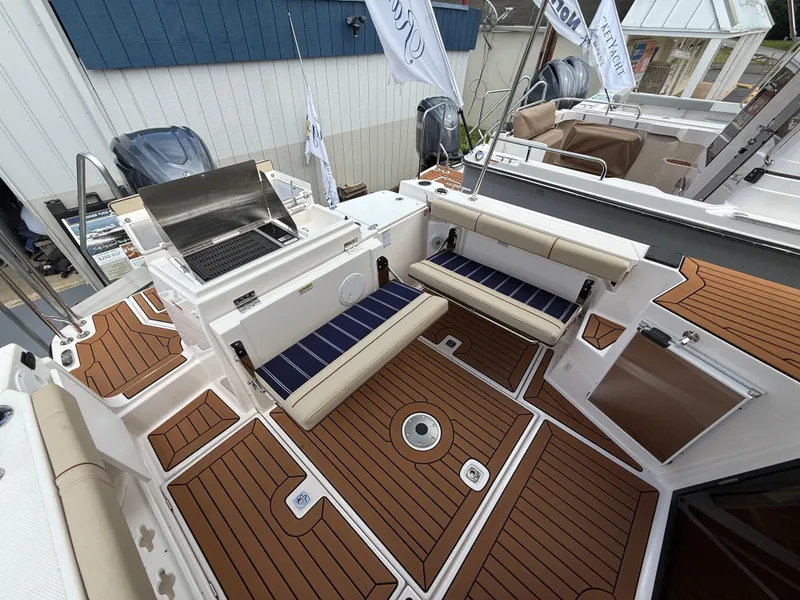 Slide: The Image of 2025 Ranger Tugs R-27 boat deck with seating and grill, featuring teak-style flooring. - 7