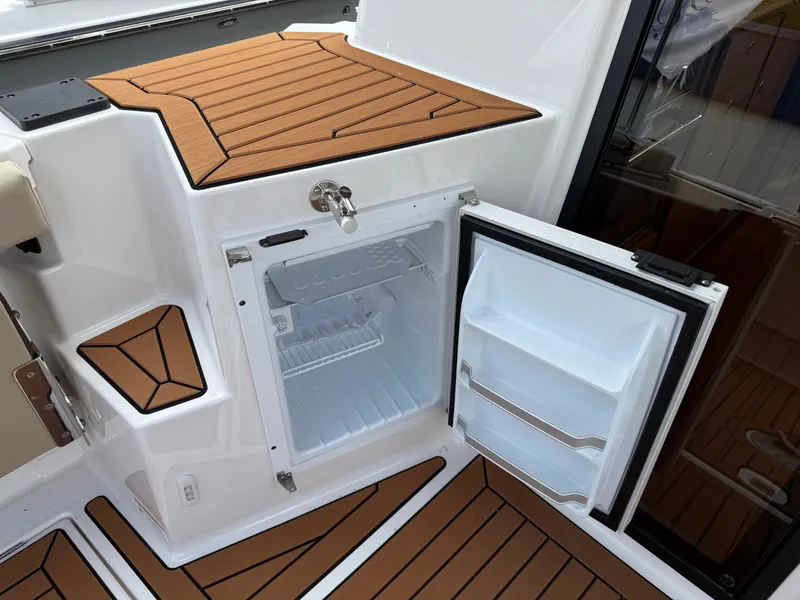 Slide: The Image of 2025 Ranger Tugs R-27 boat interior with open mini fridge and teak flooring. - 8