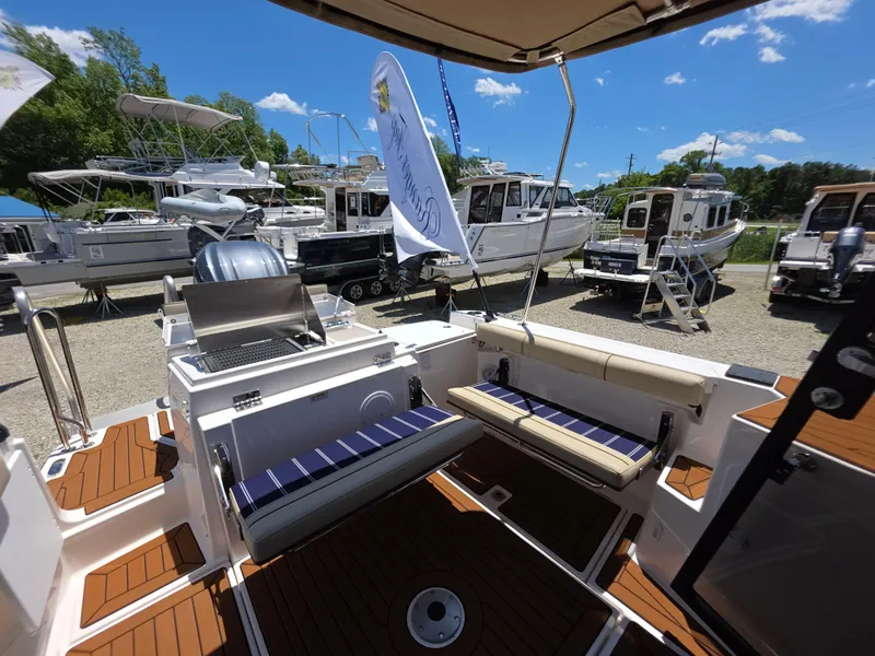 Slide: The Image of 2025 Ranger Tugs R-27 boat interior with seating, docked among other boats under a clear sky. - 3