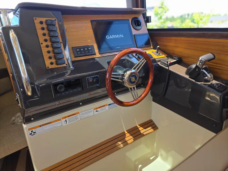 Slide: The Image of 2025 Ranger Tugs R-27 helm with Garmin display, wooden steering wheel, and control panel. - 5