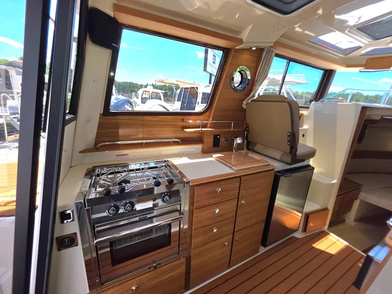 Slide: The Image of 2025 Ranger Tugs R-27 interior with modern kitchen, wood cabinetry, and stainless steel appliances. - 6