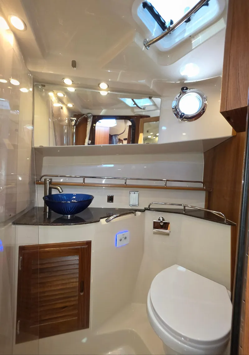 Slide: The Image of 2025 Ranger Tugs R-31 CB bathroom with modern fixtures, blue sink, and porthole window. - 11