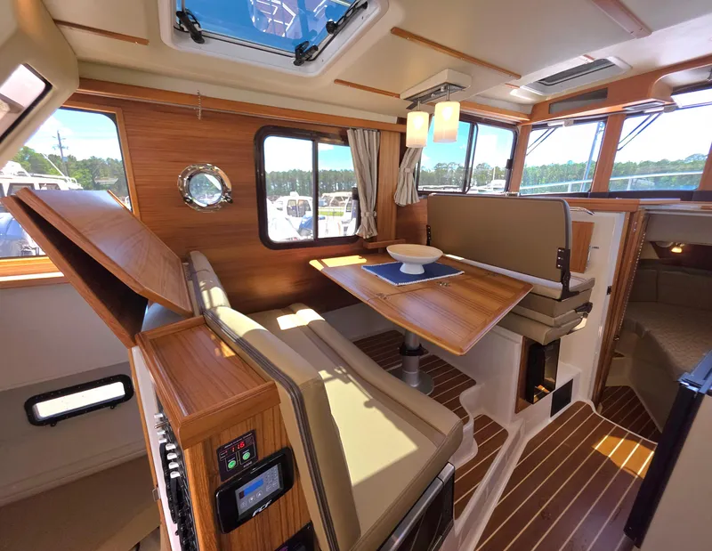 Slide: The Image of 2025 Ranger Tugs R-31 CB interior with wood finish, dining area, and natural light. - 13