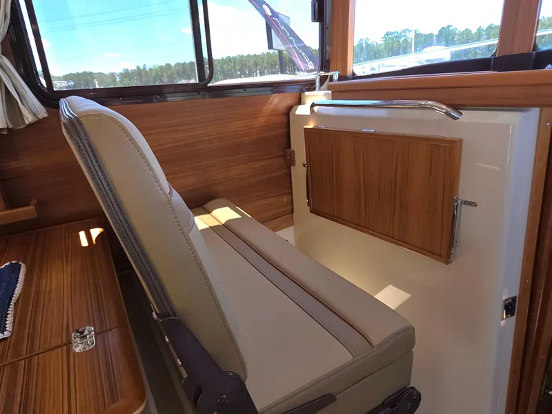 Slide: The Image of 2025 Ranger Tugs R-31 CB interior with wood paneling and cushioned seating. - 7