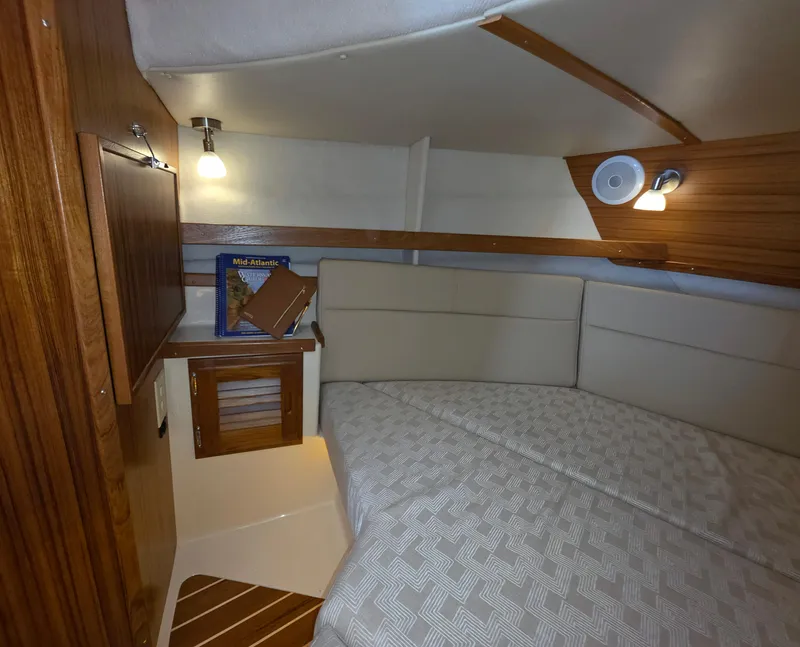 Slide: The Image of 2025 Ranger Tugs R-31 CB cabin interior with cozy bed and wooden accents. - 8