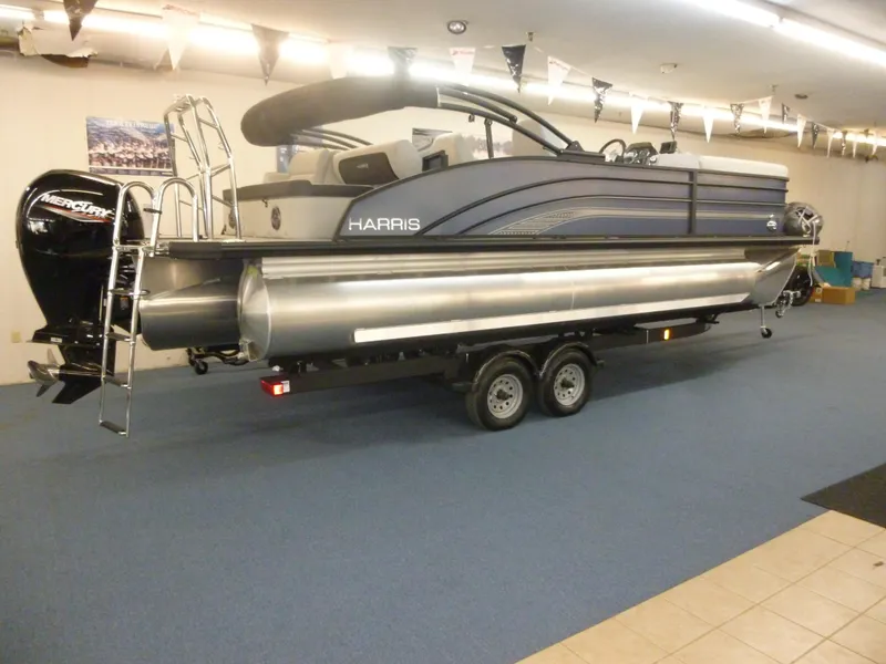 Slide: The Image of 2025 Harris CX 230 pontoon boat on trailer in showroom. - 13