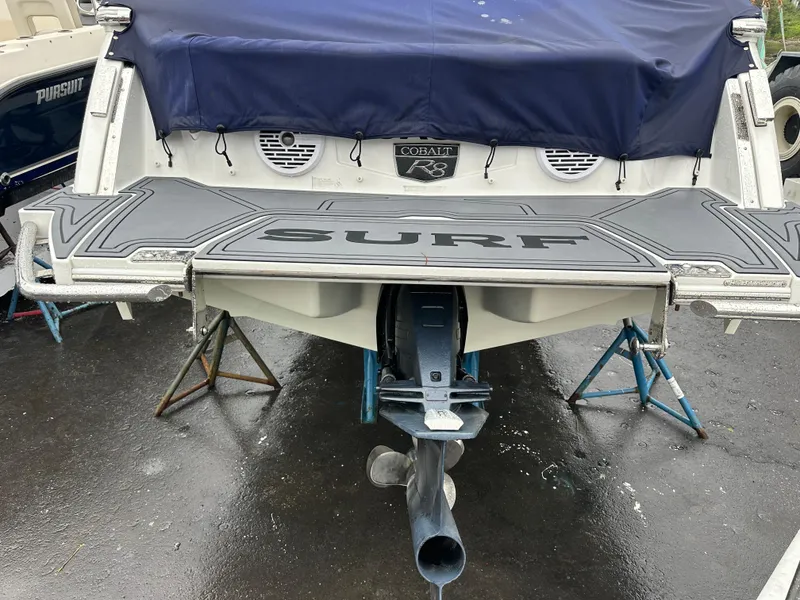 Slide: The Image of 2022 Cobalt R8 Surf boat rear view with covered deck and visible propeller. - 18