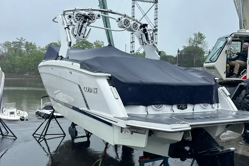 Slide: The Image of 2022 Cobalt R8 Surf boat covered, docked near water on a rainy day. - 20