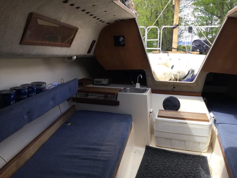 Slide: The Image of Interior of a 1987 Precision P23 sailboat with blue seating and compact kitchenette. - 15