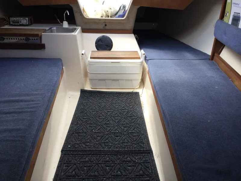 Slide: The Image of Interior of a 1987 Precision P23 sailboat with blue seating and compact kitchenette. - 17
