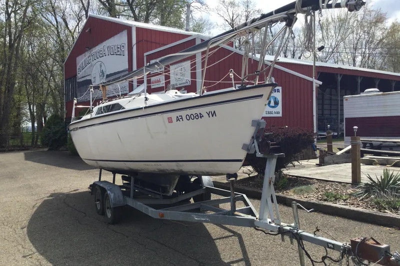 Slide: The Image of 1987 Precision P23 sailboat on trailer, parked outside a red building. - 3