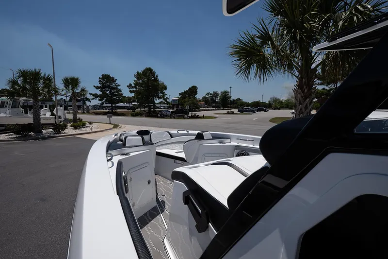 Slide: The Image of 2023 Sunsation 32 CCX boat parked, showcasing sleek design and spacious seating under clear blue sky. - 21