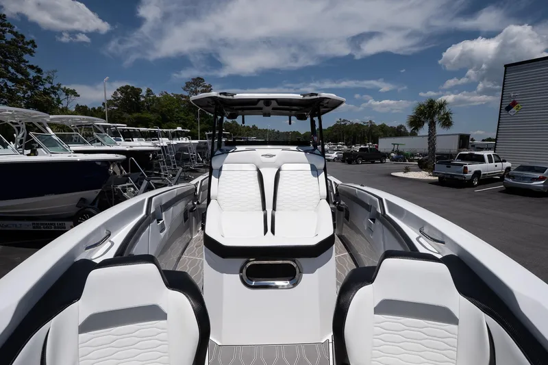 Slide: The Image of 2023 Sunsation 32 CCX boat with sleek white seating and modern design, docked under a blue sky. - 25