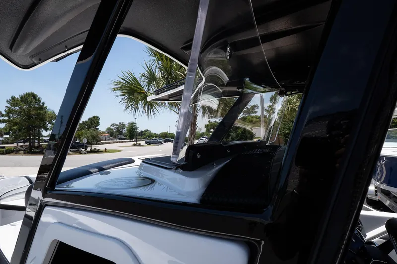 Slide: The Image of 2023 Sunsation 32 CCX boat windshield and console, with palm trees in the background. - 26