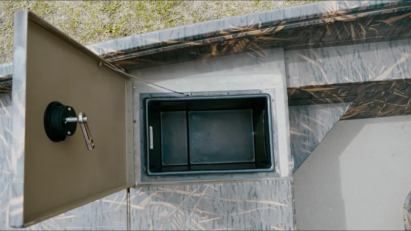 Slide: The Image of Open storage compartment in 2025 G3 18CC boat, featuring camo design and secure latch. - 10