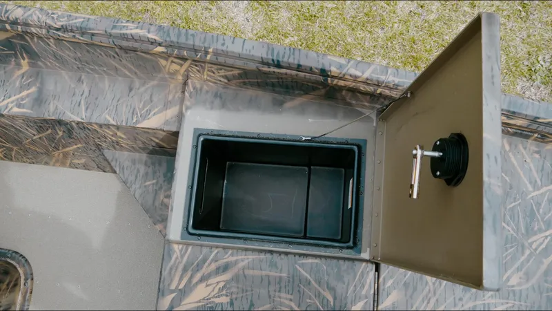 Slide: The Image of Open storage compartment in 2025 G3 18CC boat, featuring camo design and secure latch. - 8