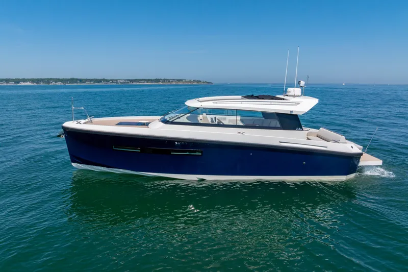 The Image of 2023 Delta Powerboats 33 Coupe cruising on open water under clear blue skies. - 1