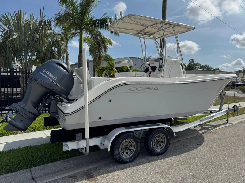 Slide: The Image of 2020 Cobia 220 Center Console boat on trailer with Yamaha outboard, parked near palm trees. - 3